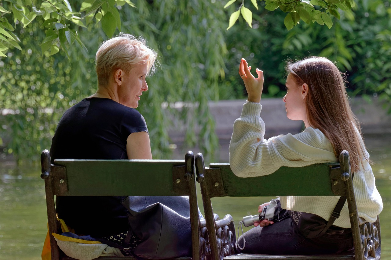 Two people sitting on a park bench having a relaxed conversation