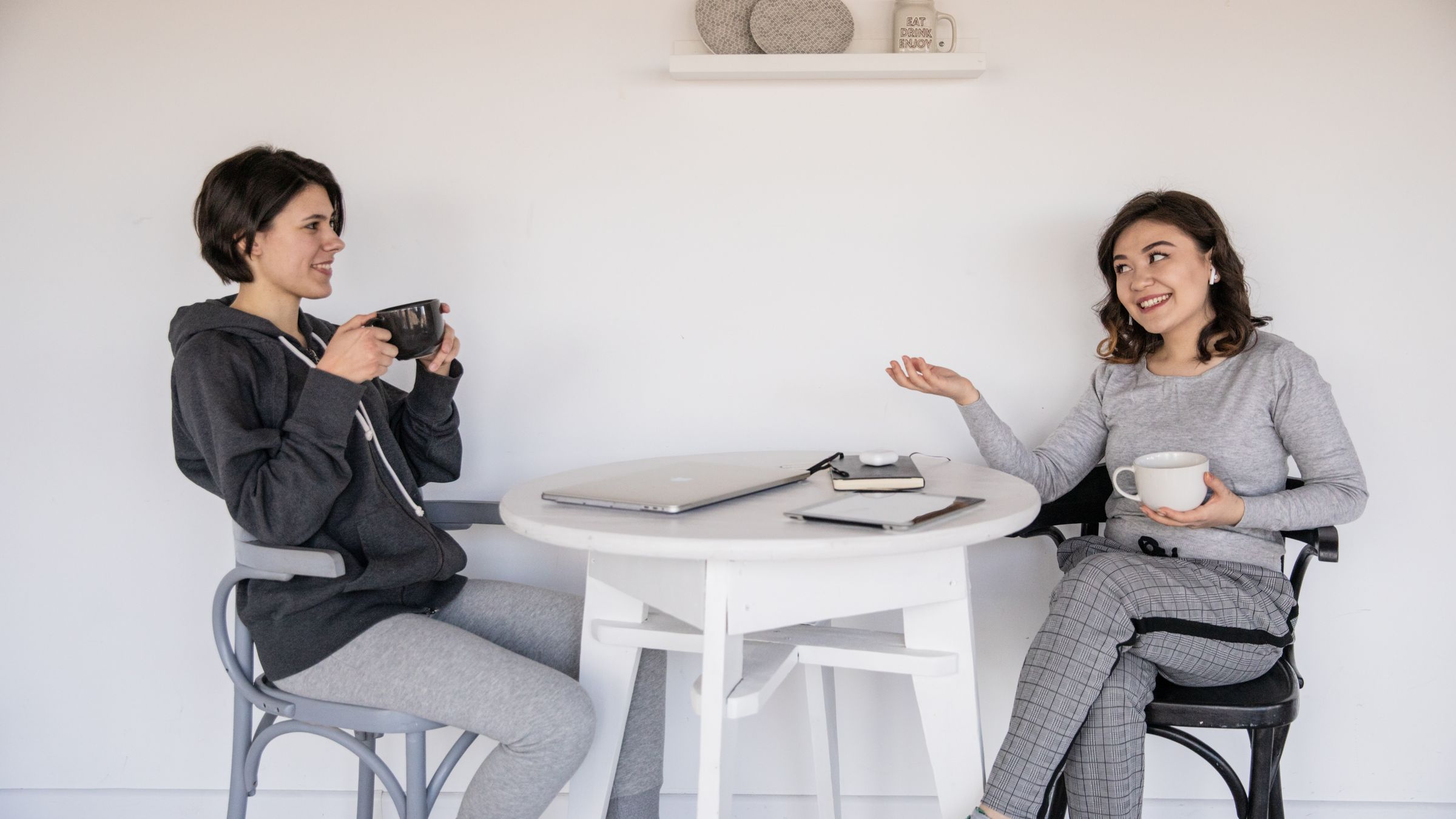 Two people smiling and chatting over coffee at a table