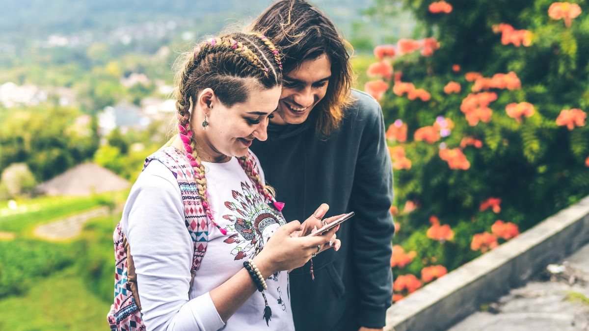 A man and woman smiling together as they look at a phone screen