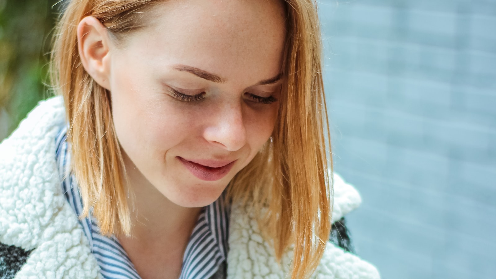 A young woman with a warm, genuine smile looking down as if reading a message mid-chat